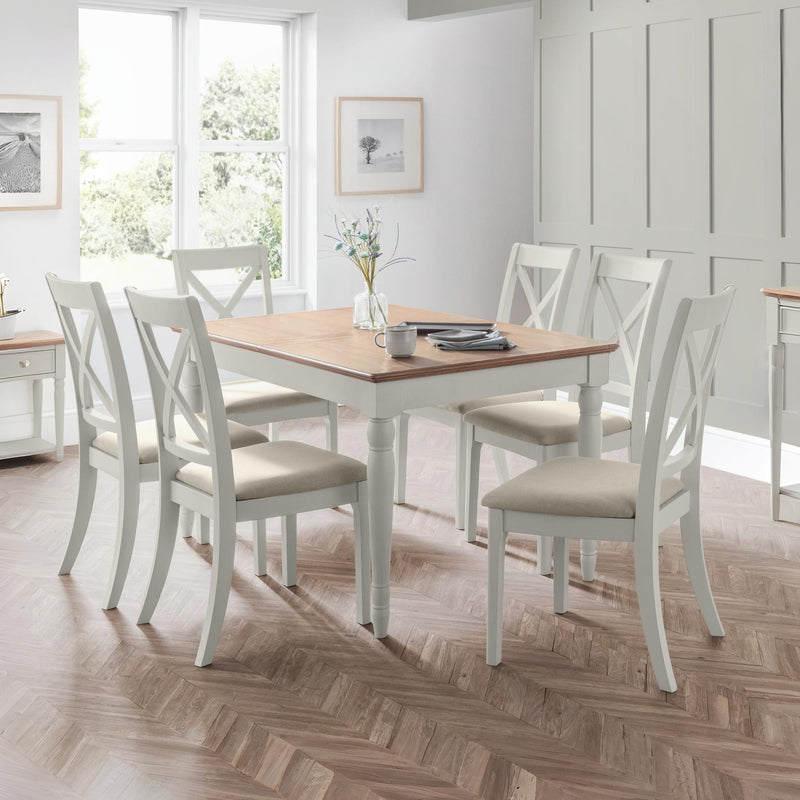 Dining room with a wooden table and white chairs on a wooden floor.