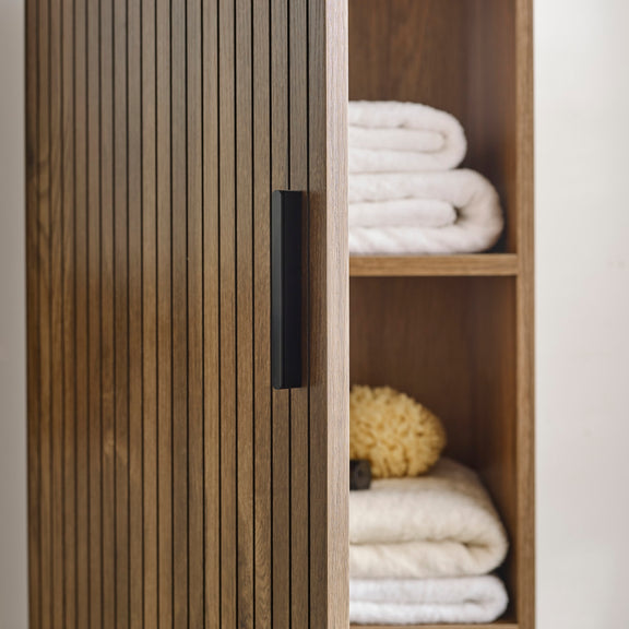 Wooden wardrobe with open door revealing folded clothes inside.