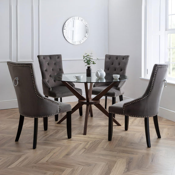 Dining room with a glass table and brown chairs on a wooden floor.
