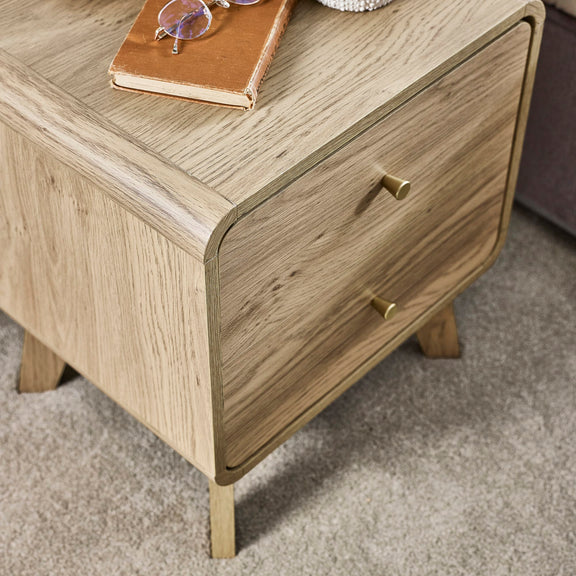 Wooden nightstand with a drawer, notebook, and glasses on top.