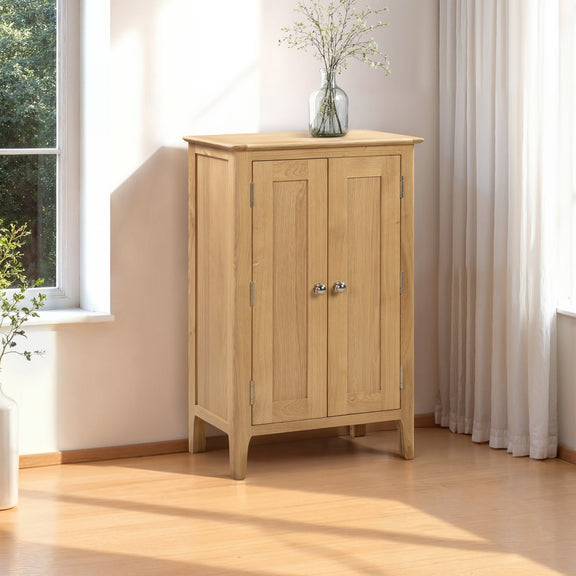Wooden cabinet with two doors in a bright room with a window and white curtains.