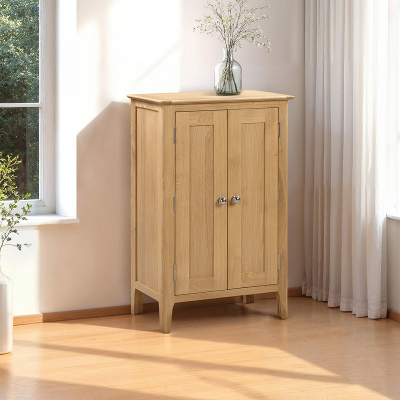 Wooden cabinet with two doors in a bright room with a window and white curtains.