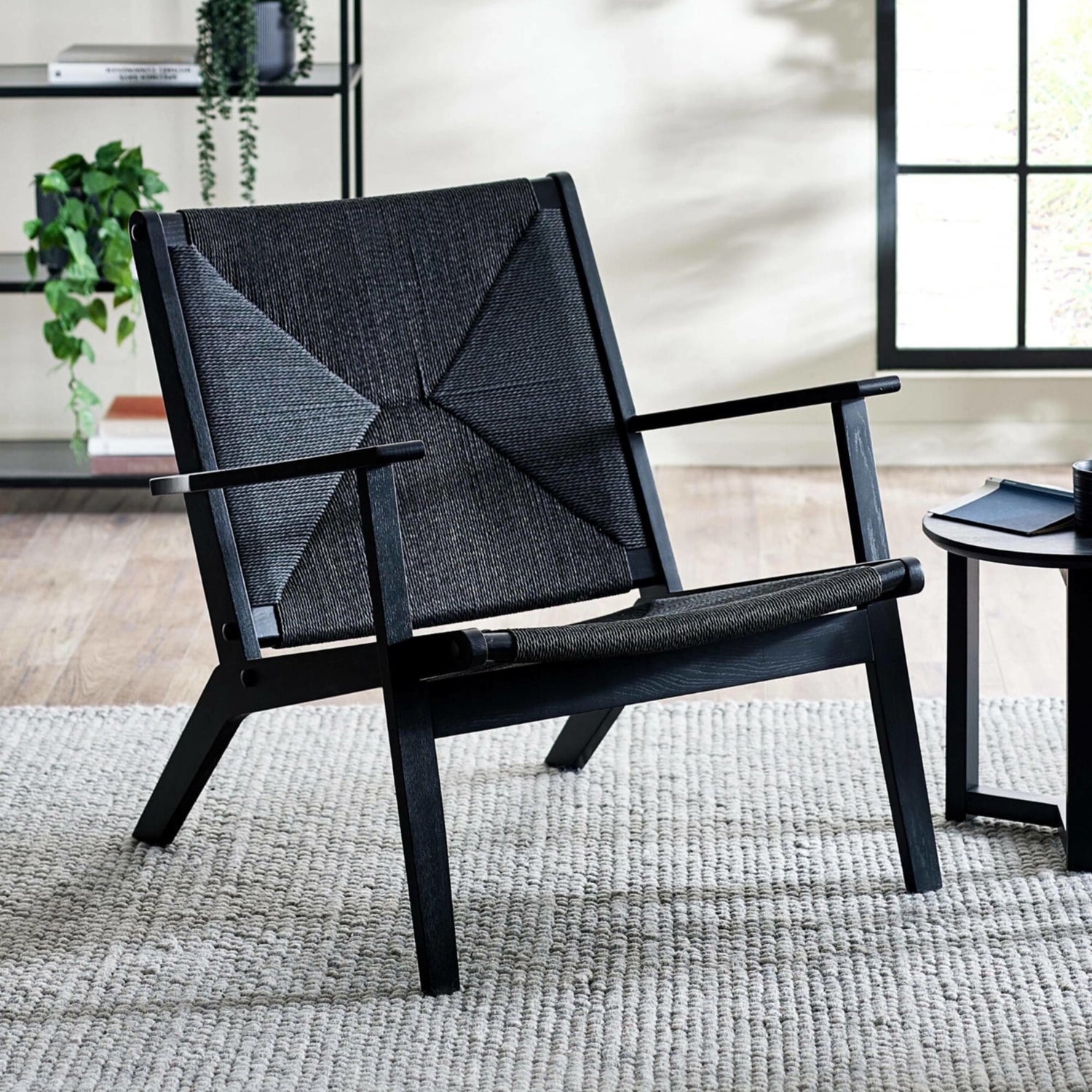 Modern black chair with geometric pattern in a room with a rug and side table.