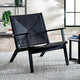 Modern black chair with geometric pattern in a room with a rug and side table.