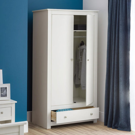 White wardrobe with mirror in a room with blue walls and a curtain.