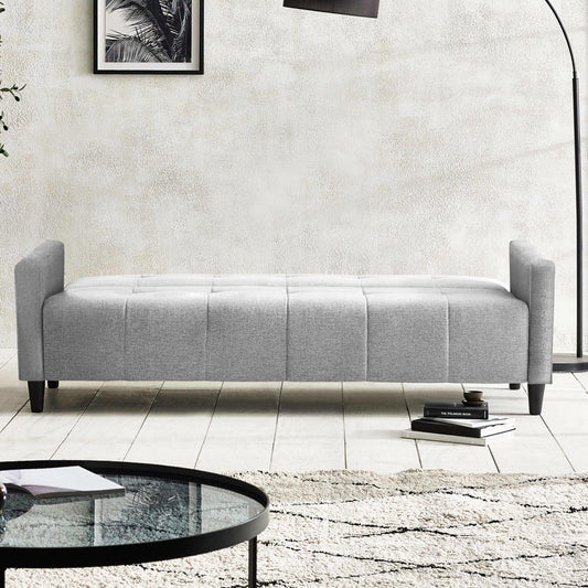 Gray upholstered bench in a modern living room setting with a coffee table and books.