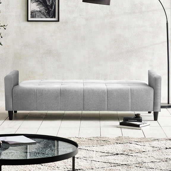 Gray upholstered bench in a modern living room setting with a coffee table and books.