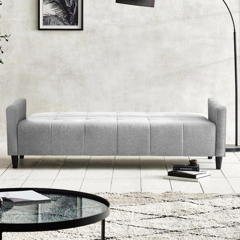 Gray upholstered bench in a modern living room setting with a coffee table and books.