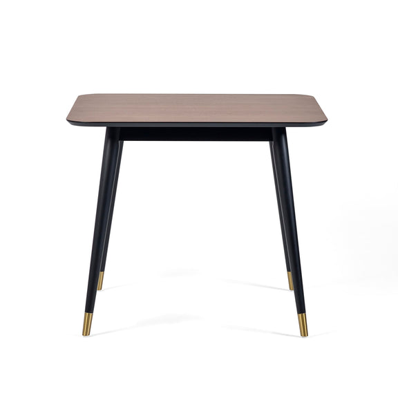 Square table with wooden top and black legs with gold accents on a white background