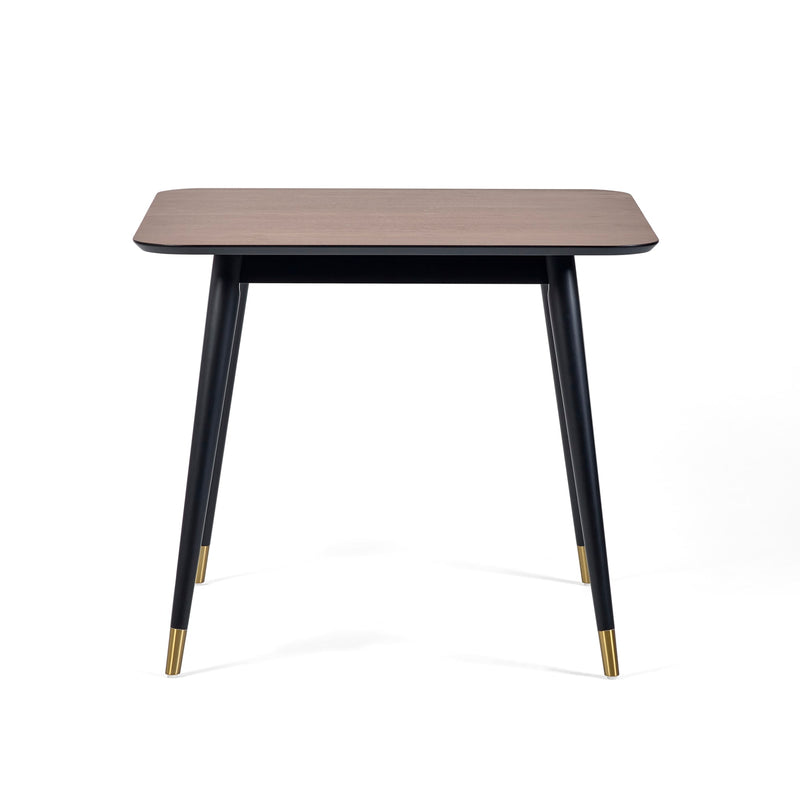 Square table with wooden top and black legs with gold accents on a white background