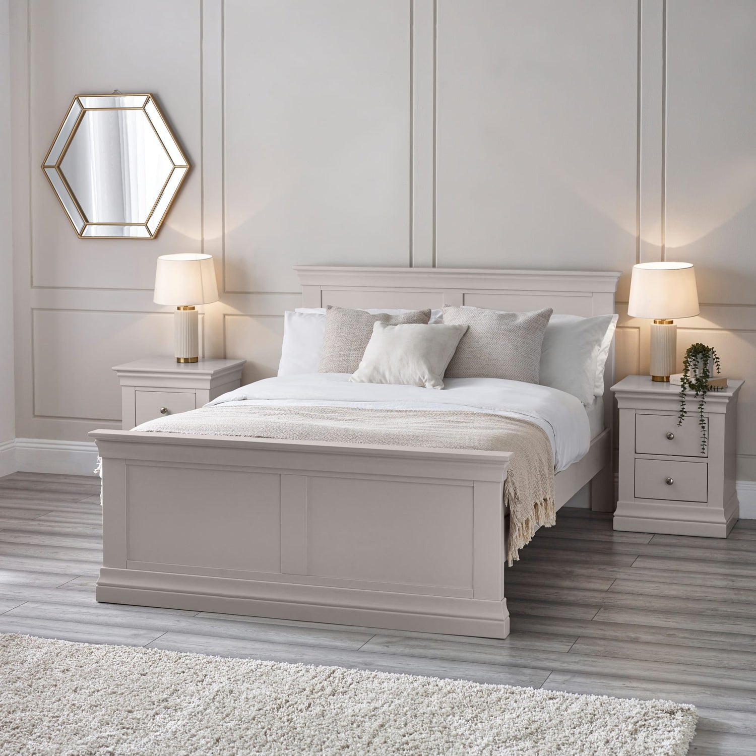 Neatly made bed in a bedroom with two nightstands and lamps.