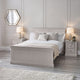 Neatly made bed in a bedroom with two nightstands and lamps.