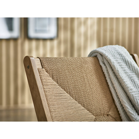 Woven chair with a blanket draped over it in a room setting