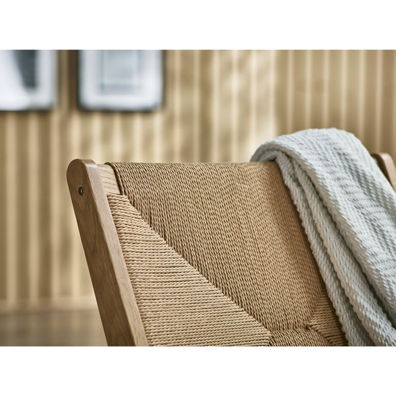 Woven chair with a blanket draped over it in a room setting