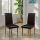 Two brown chairs on a wooden floor with a plant and window in the background