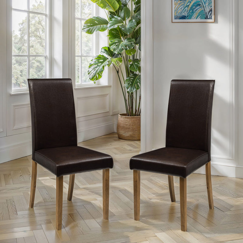 Two brown chairs on a wooden floor with a plant and window in the background