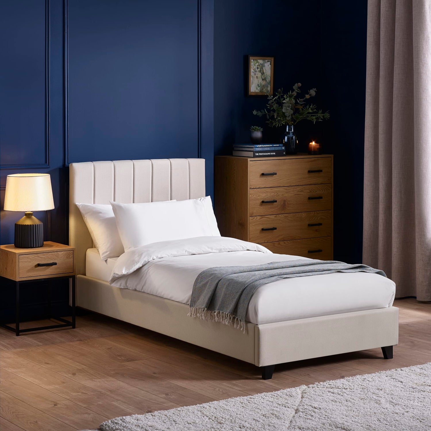 Neatly made bed with beige headboard in a bedroom setting.