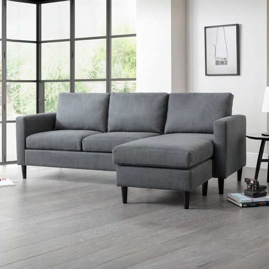 Gray sectional sofa in a room with large windows and a lamp.
