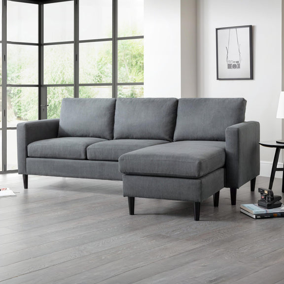 Gray sectional sofa in a room with large windows and a lamp.