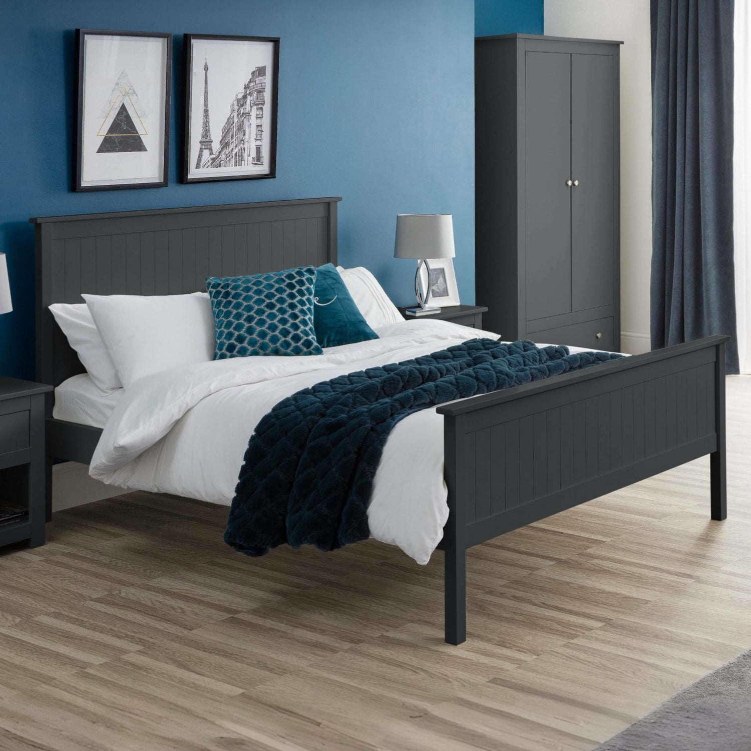 Bedroom with dark gray bed frame, white bedding, and blue accents against a blue wall.