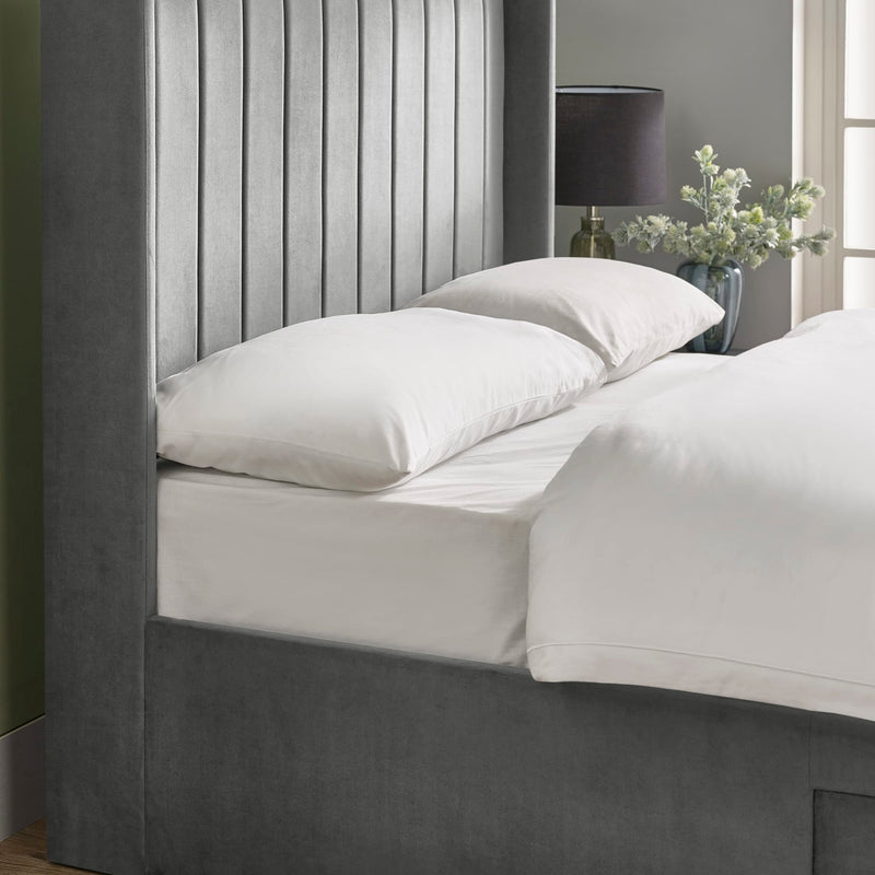 Bed with white bedding and pillows in a bedroom setting.