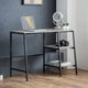 Modern desk with laptop, camera, and books against a gray wall.