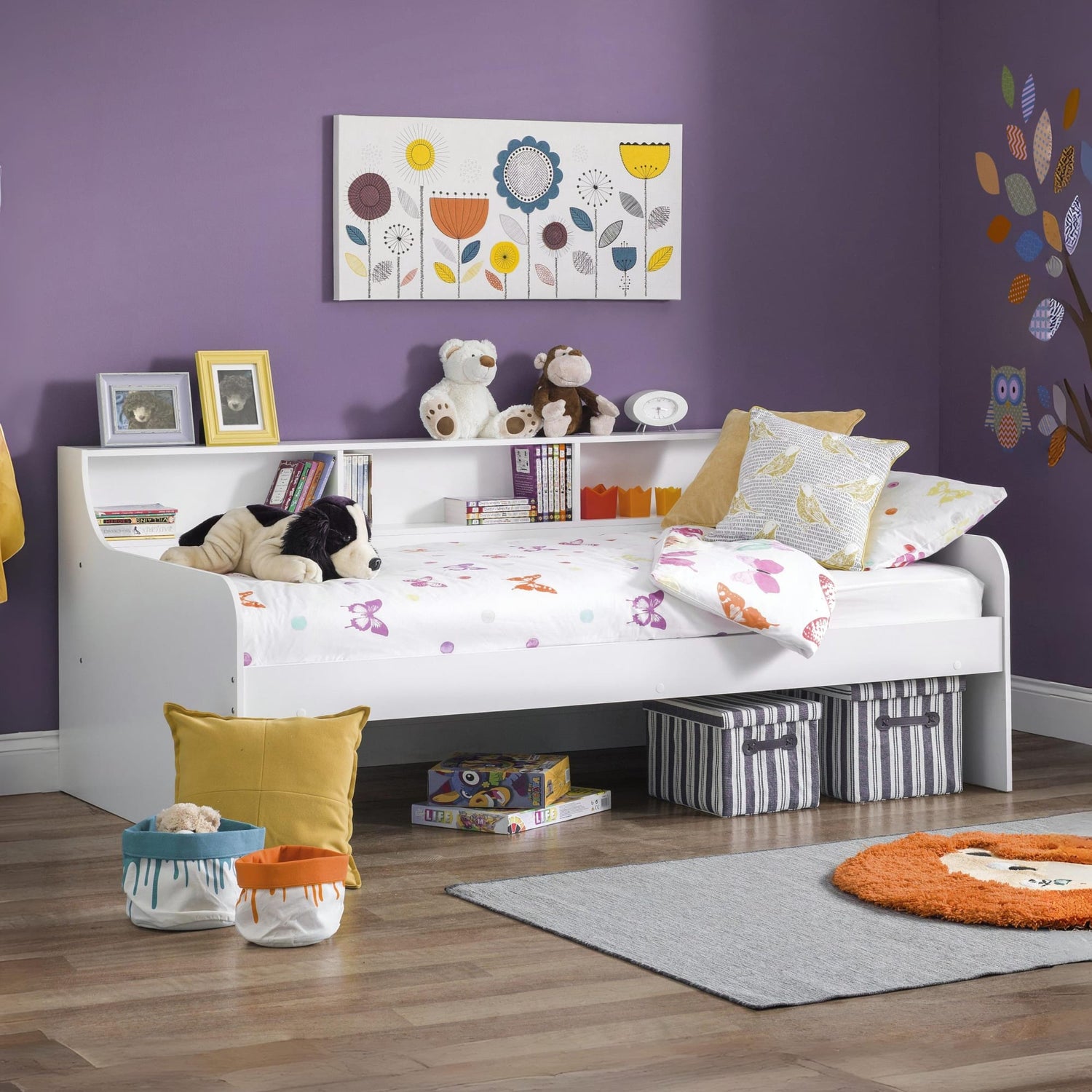 Children's bedroom with a bed, toys, and decorative elements on a purple wall.