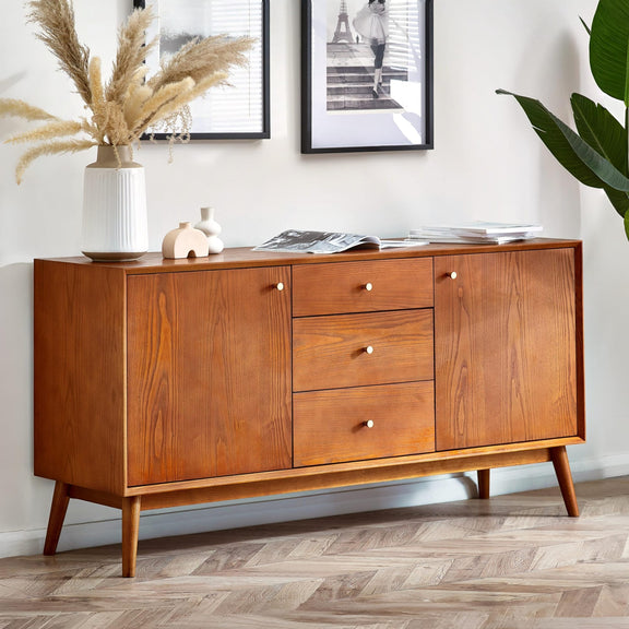 Wooden sideboard with decorative items in a room with framed pictures and plants.