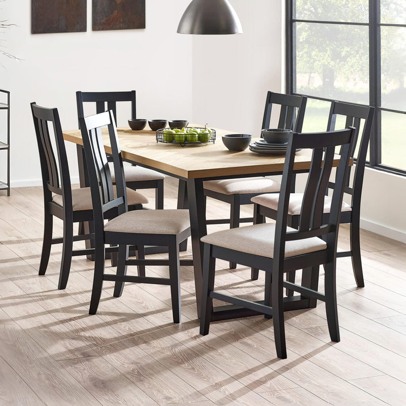 Dining room with a wooden table and black chairs with beige cushions.