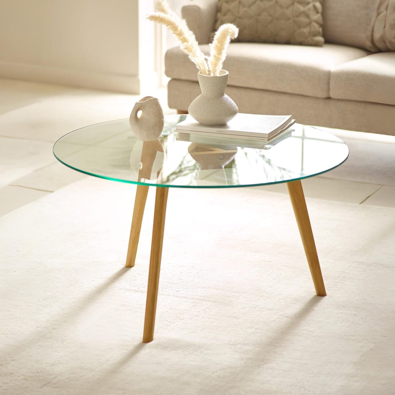 Glass coffee table with wooden legs in a living room setting