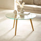 Glass coffee table with wooden legs in a living room setting