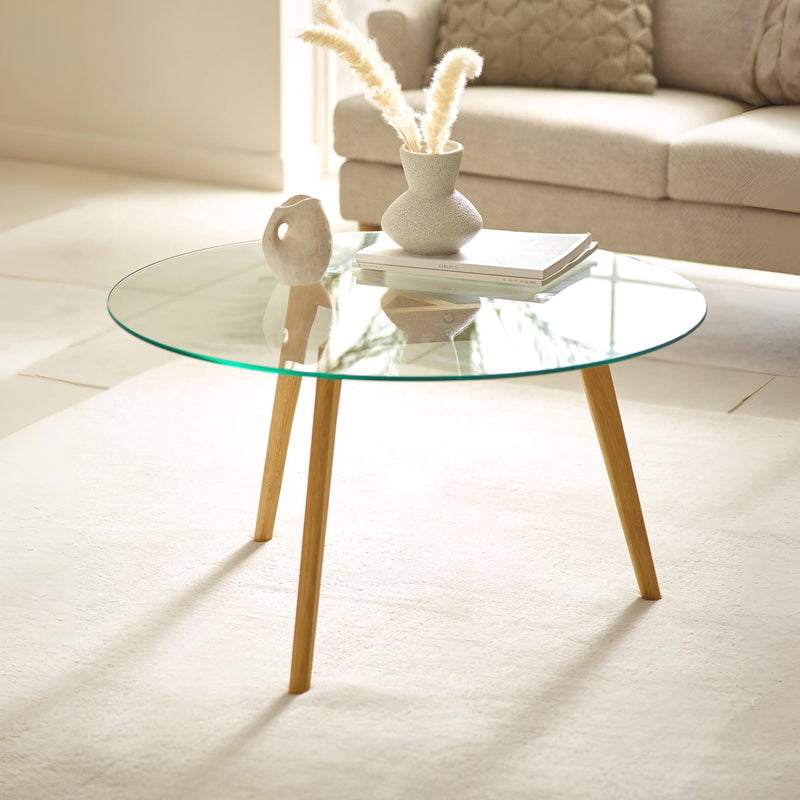Glass coffee table with wooden legs in a living room setting