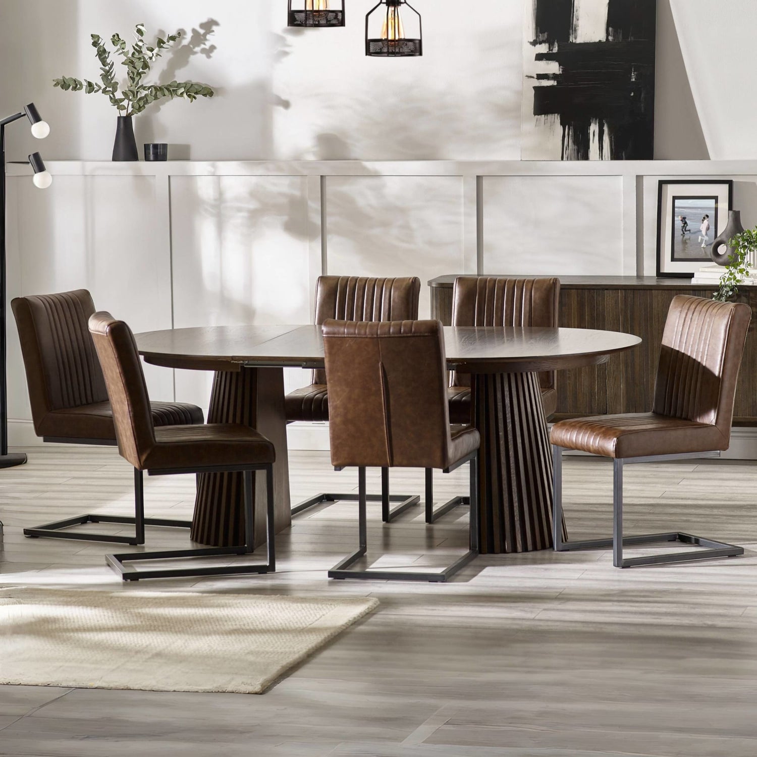 Dining room with a round wooden table and brown chairs in a modern interior setting.