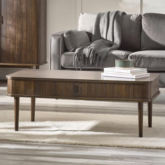 Wooden coffee table in a living room with a gray sofa and books on top