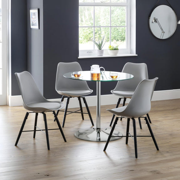 Dining area with round table and four gray chairs in a room with a window and dark walls.