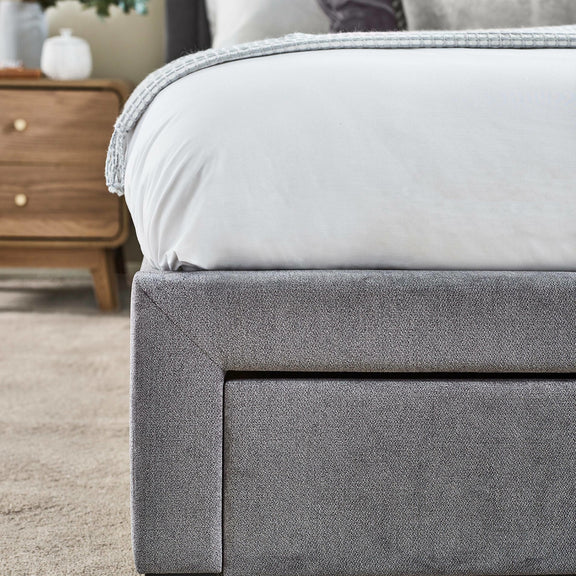 Gray upholstered bed frame with a white mattress in a bedroom setting.