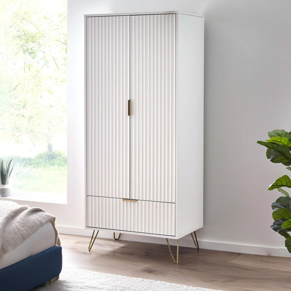 White cabinet with gold legs in a room with a window and plant