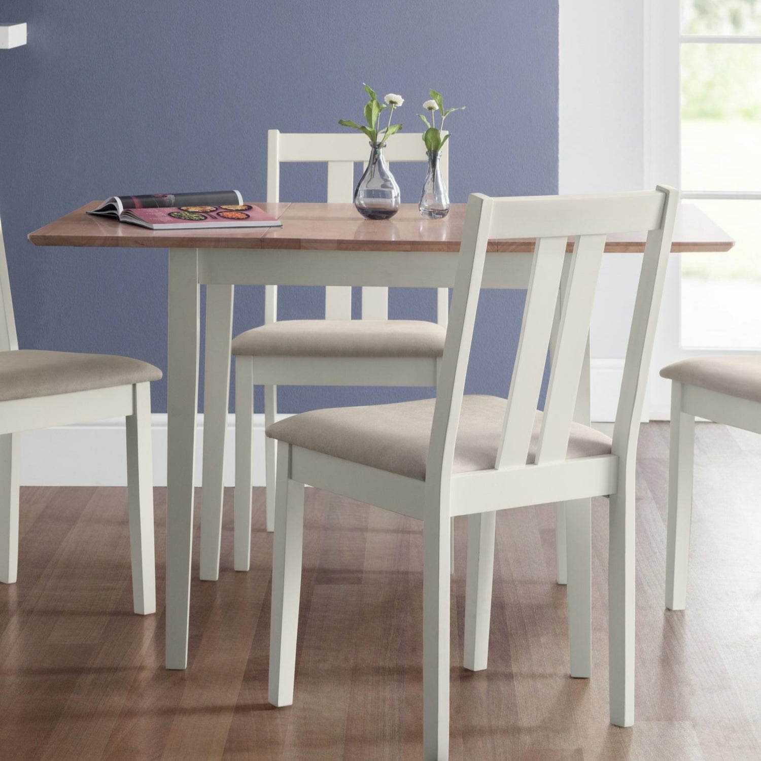 Dining table with chairs in a room with a blue wall and window.