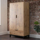 Wooden wardrobe against a brick wall with a plant to the right