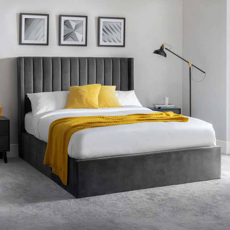 Gray upholstered bed with yellow blanket and pillows in a modern bedroom setting.
