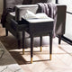 Black side table with gold legs next to a gray sofa with an open book on top.