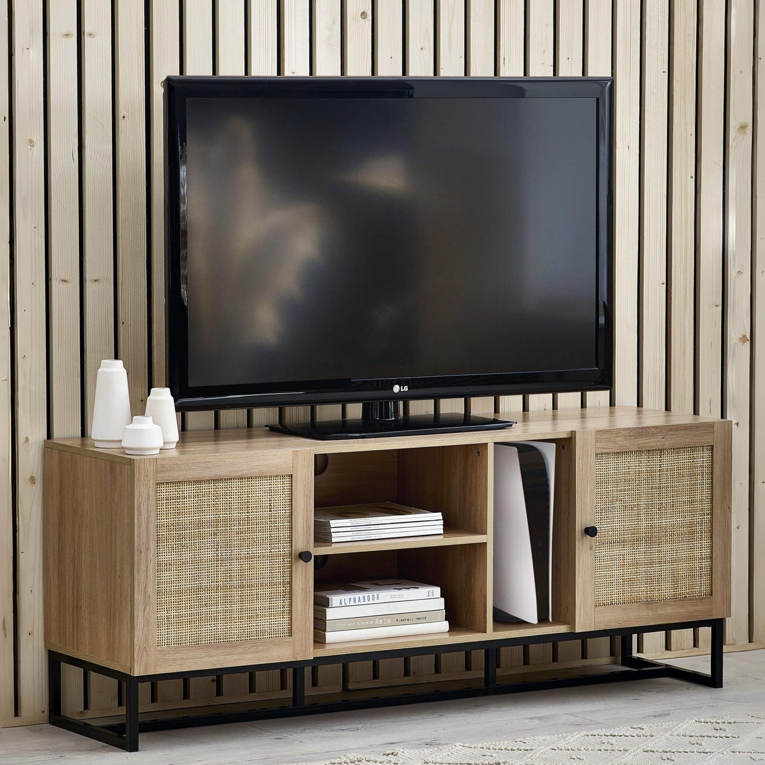 Wooden TV stand with a television on top against a wooden paneled wall.