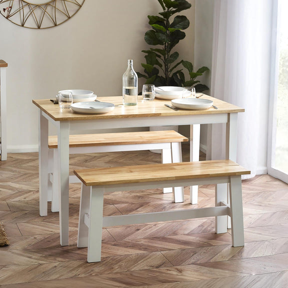 Dining table with benches in a room with a plant and window.