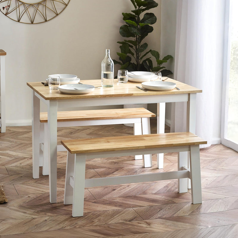 Dining table with benches in a room with a plant and window.