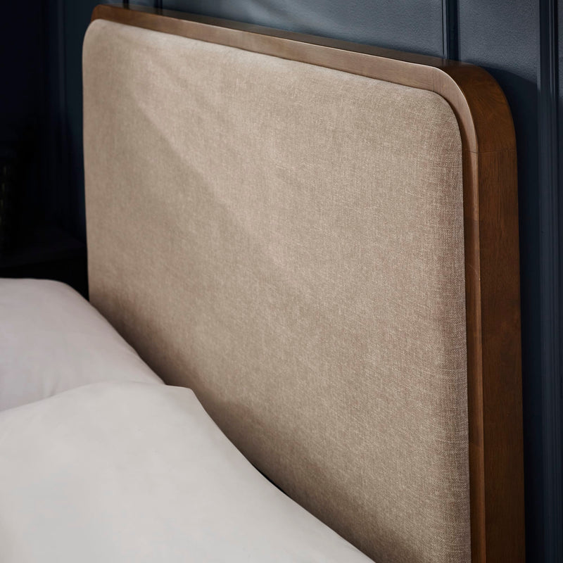 Close-up of a beige upholstered headboard with wooden frame.