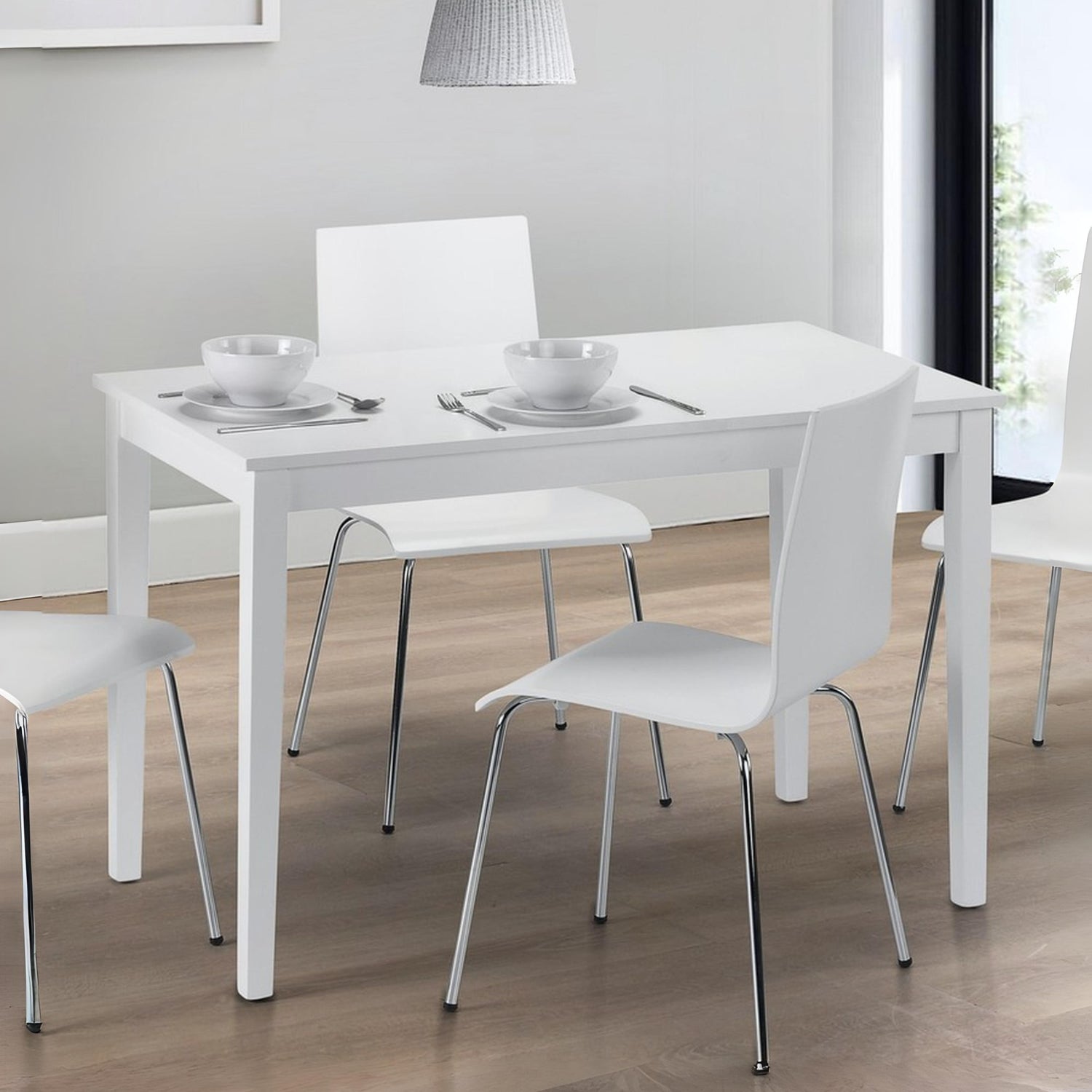 White dining table with chairs in a room with a gray wall and wooden floor.