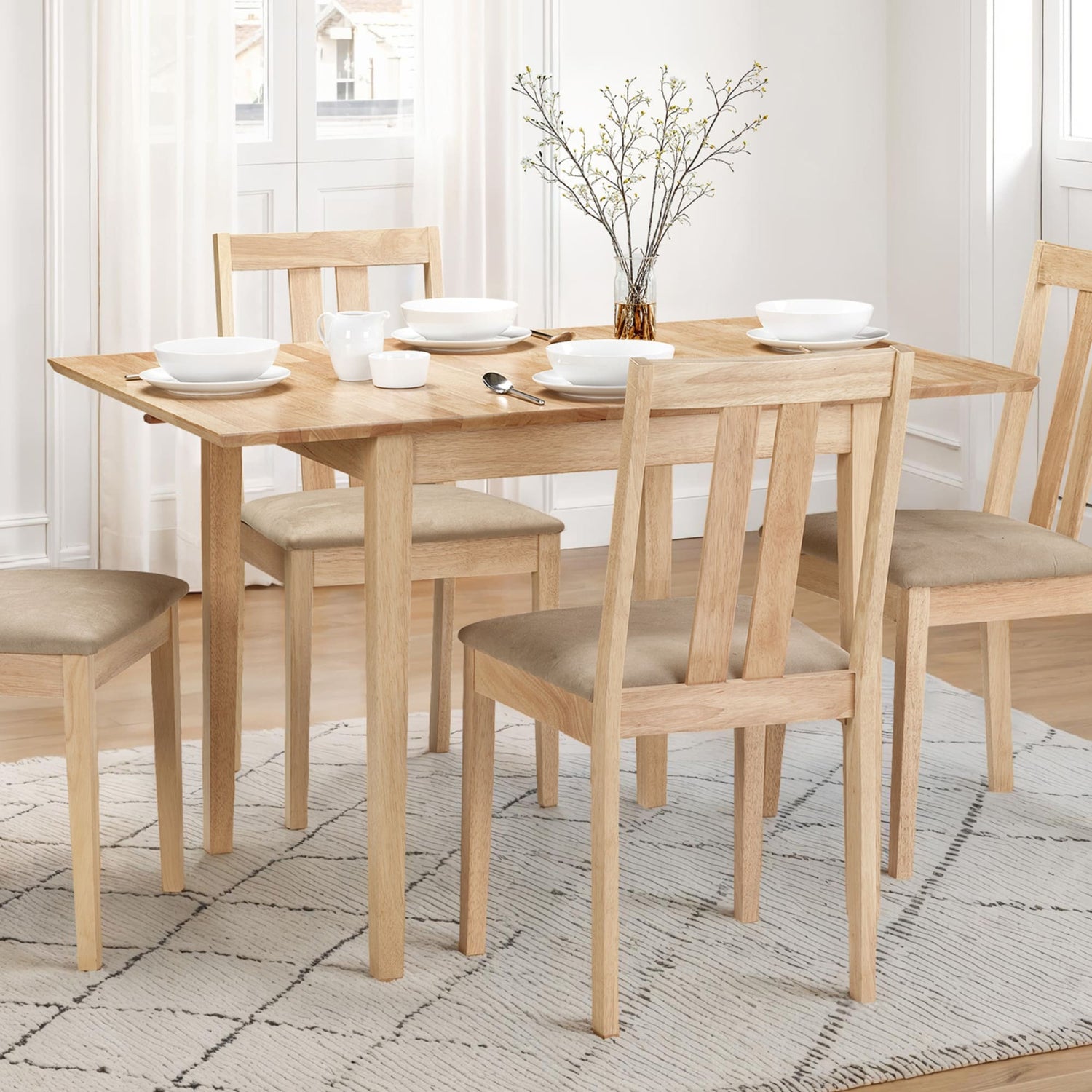 Dining table set with chairs and plates in a bright room