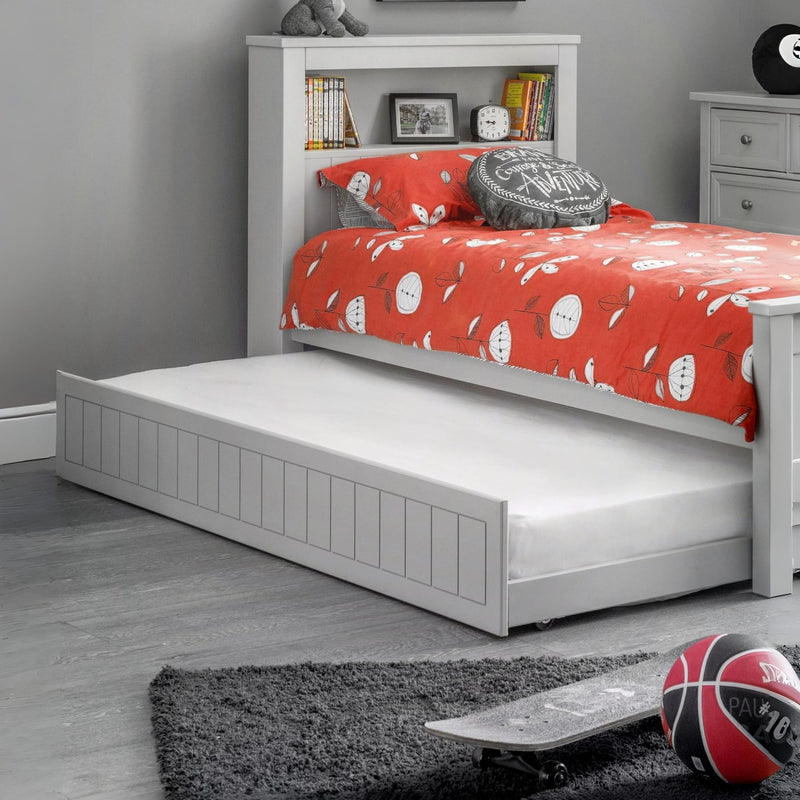 Children's bed with red bedding and white drawers in a room setting.