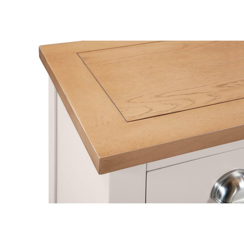 Close-up of a wooden kitchen countertop with a white cabinet and silver sink in the background.