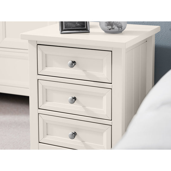 White nightstand with three drawers and silver knobs in a bedroom setting.